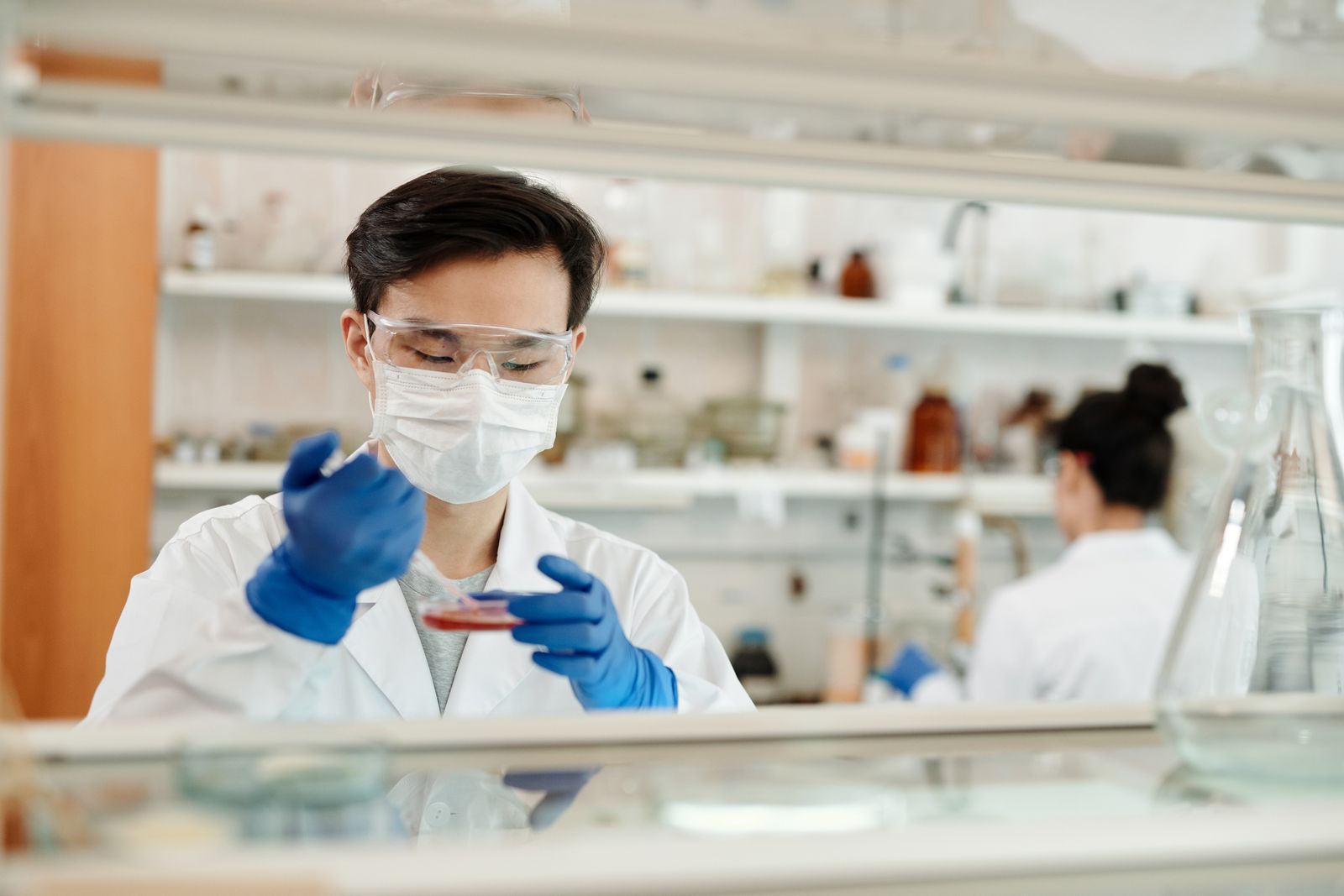 Onderzoeker in laboratoriumjas werkt aan een experiment met een petrischaal